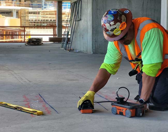 Technician scanning a concrete slab with ground penetrating radar